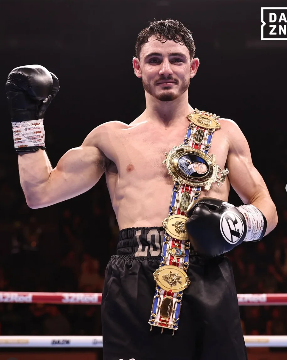 Louie O’Doherty celebrates in the ring wearing a championship belt